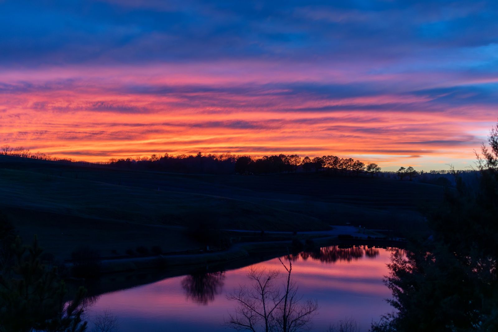 Sunset over rolling hills reflected in a pond